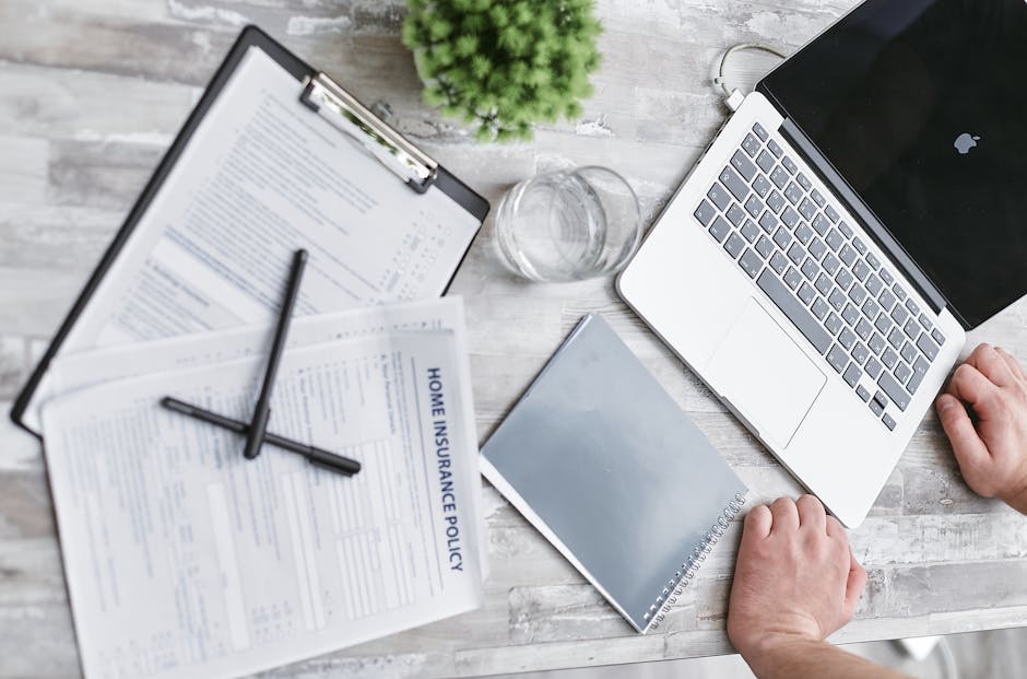 Top view of home insurance forms laptop and docu