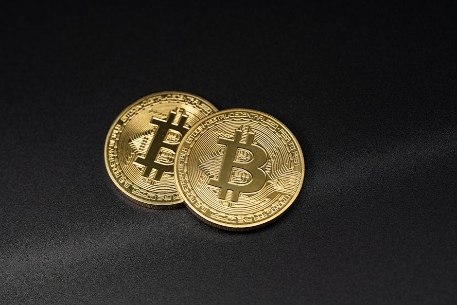 Two gold Bitcoin coins resting on a sleek black su