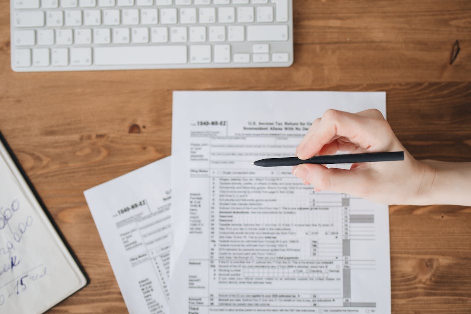 Close up of a hand holding a pen over US tax forms 1
