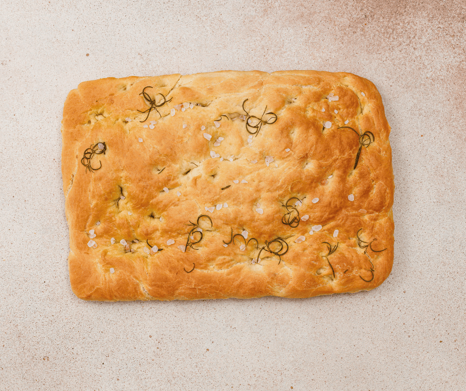 A whole, golden brown rosemary focaccia bread freshly baked in a pan.