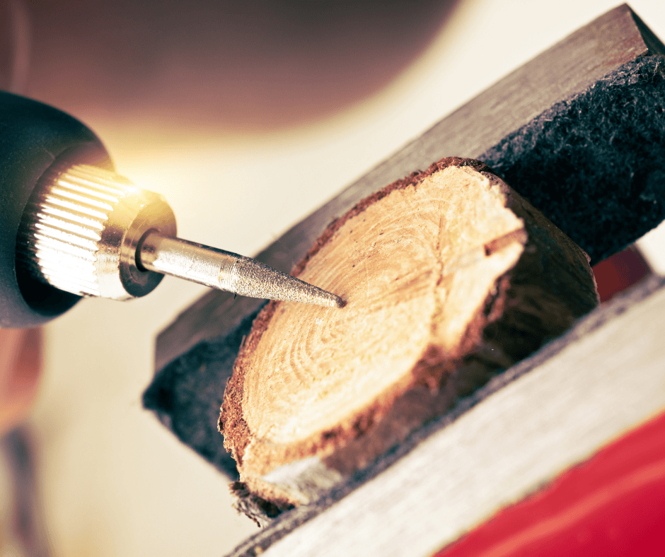 Close-up of a diamond-tip engraving pen personalizing a small wood slice.