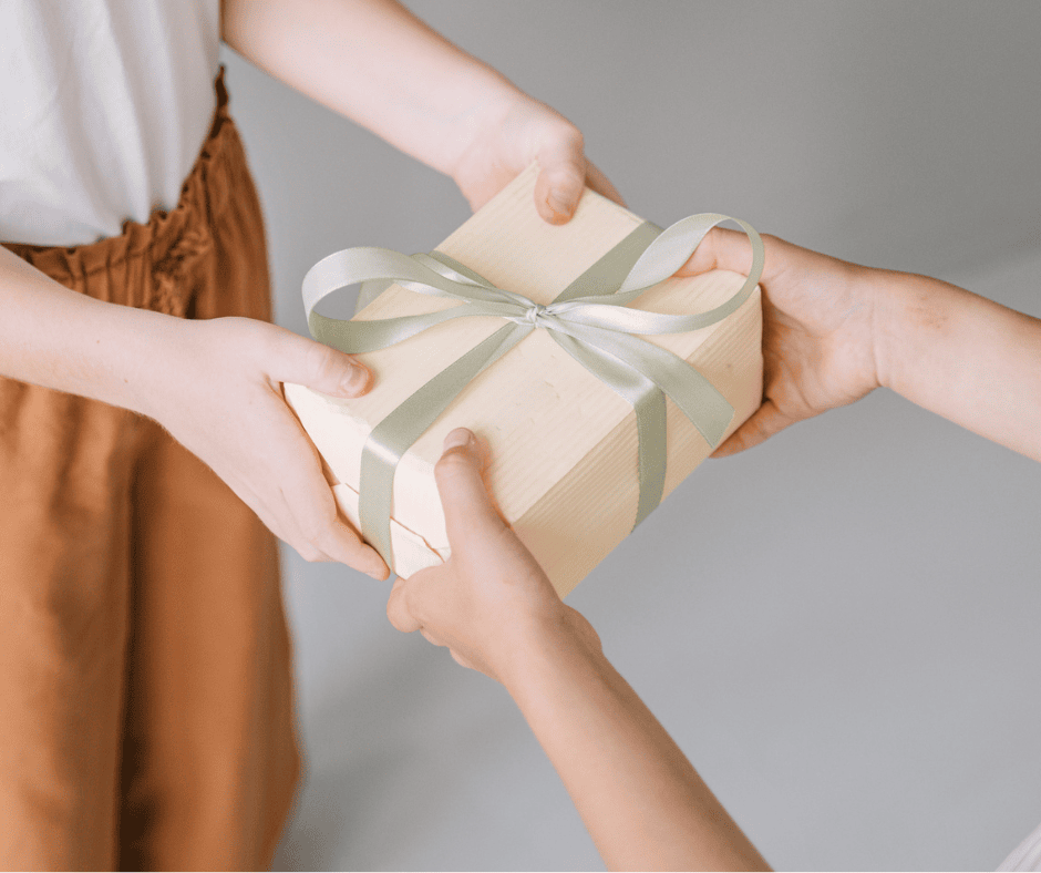 Two people exchanging a hand-personalized DIY gift box with a green ribbon.