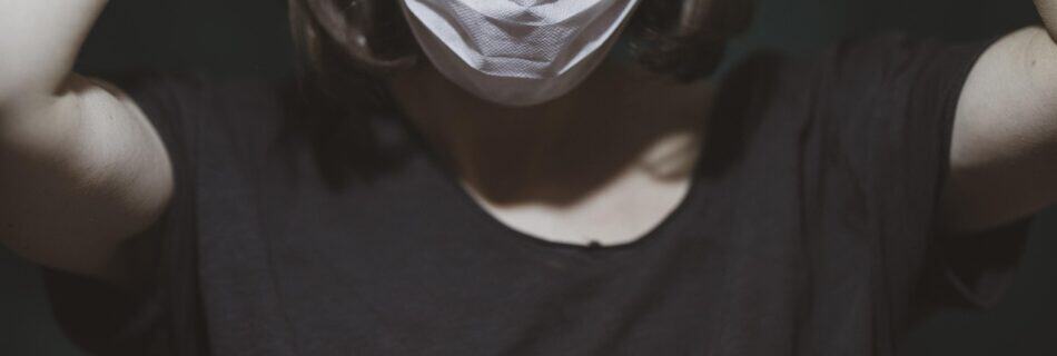 Healthcare professional wearing a mask, experiencing stress and burnout, highlighting the emotional toll faced by healthcare workers in demanding environments.
