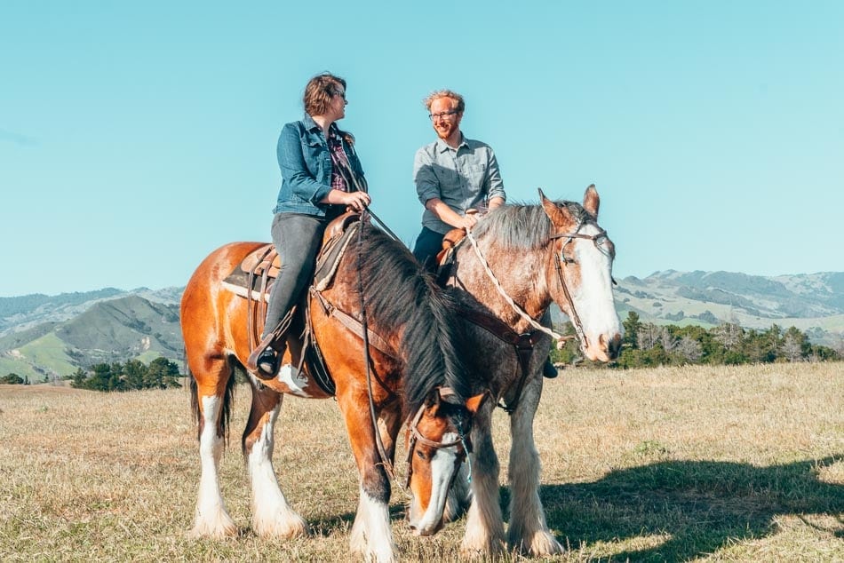 Lia and Jeremy riding Clydesdale horses in Cambria, California on the Central Coast