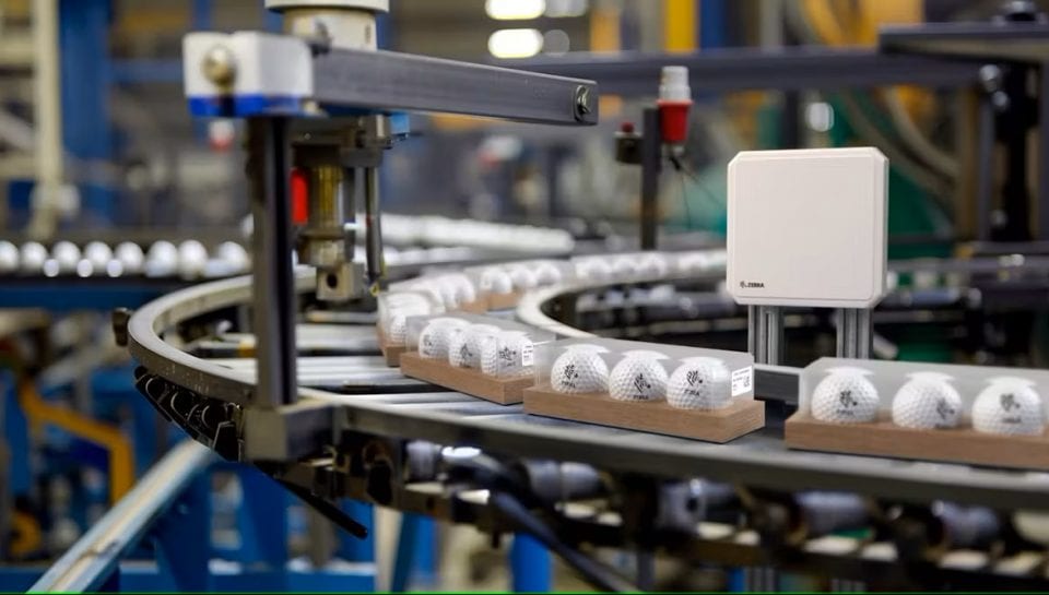 iot-beneficios-industria Cadena de producción con bolas de golf en una cinta transportadora, utilizada en una noticia.