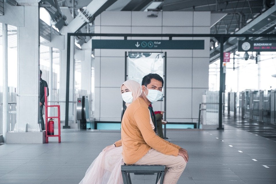 Two people sitting with masks on