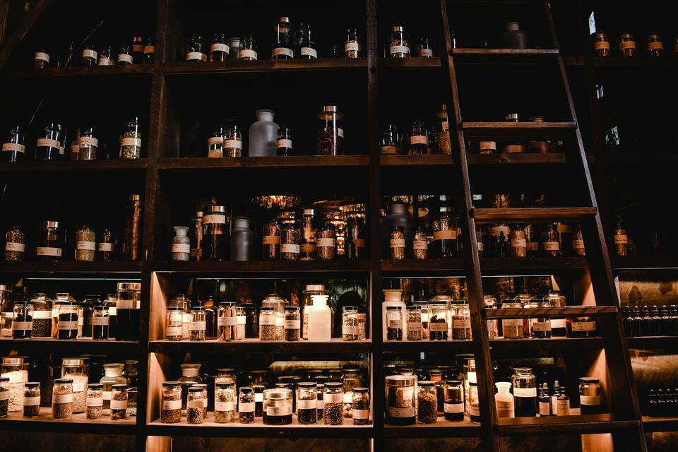 Historisches Apothekenregal mit vielen Standgefäßen und einer Holzleiter.