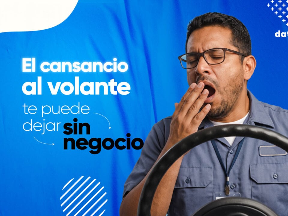 Conductor de transporte de carga o pasajeros bostezando por cansancio al volante mientras conduce por una carretera, con las manos en el volante y un dispositivo GPS visible en el tablero del vehículo.