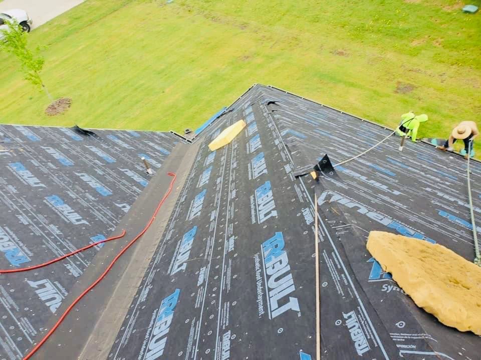 JDCC Roofing crew installing synthetic roof underlayment on a residential roof during a replacement project in Weatherford, TX