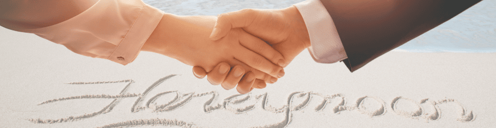 Image of shaking hands with honeymoon written in sand in the background for Postnuptial agreements header image