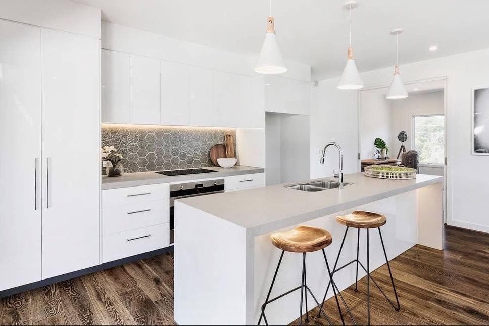 A modern custom-made kitchen with a bespoke design. Waterfall stone bench tops in a light color.