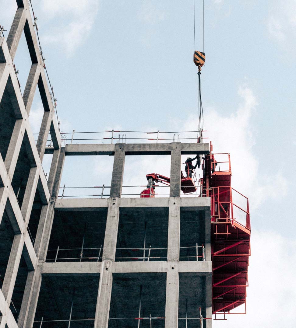 Construction site with a concrete building under development and red scaffolding, representing a commercial or residential building project.