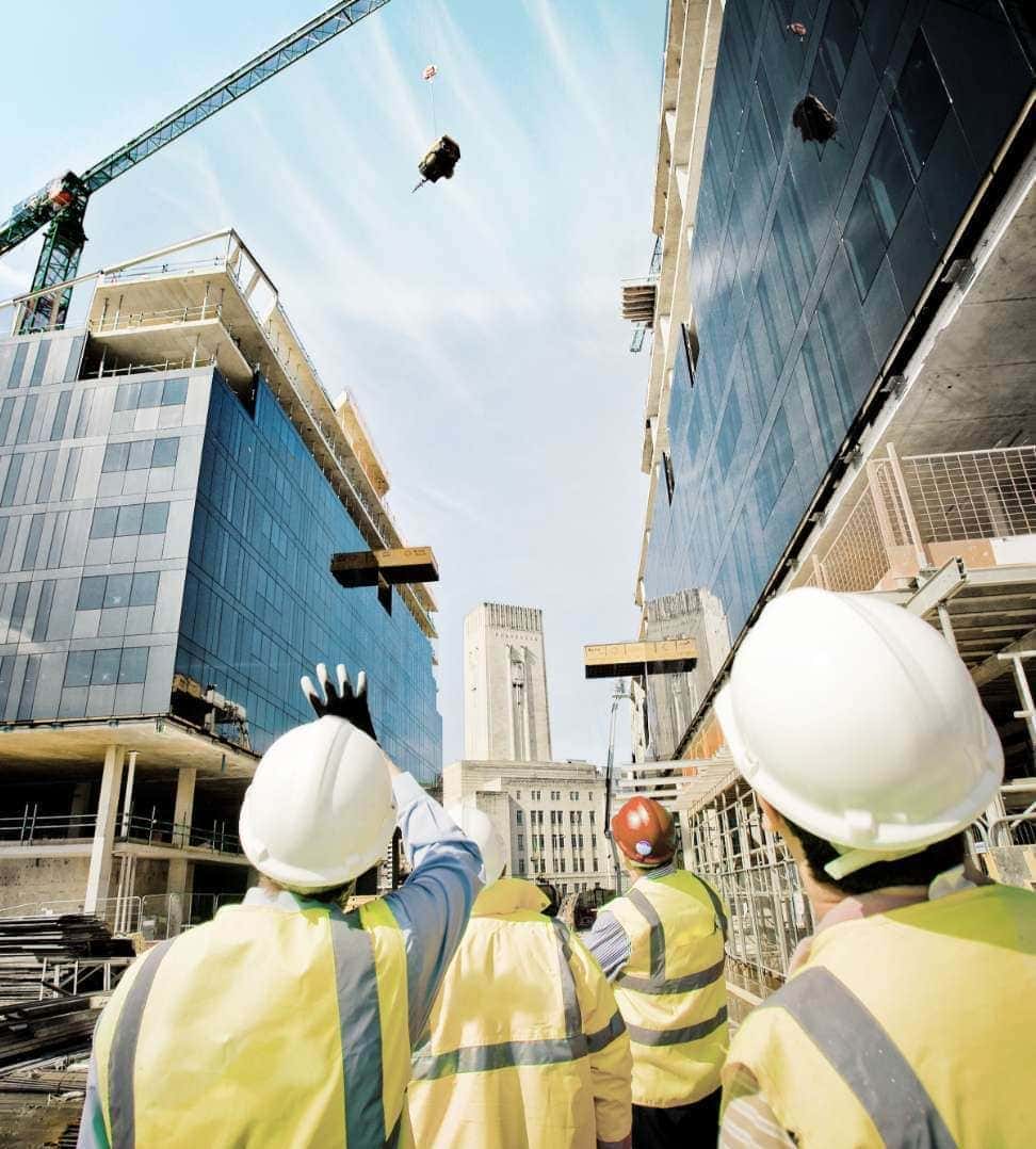 Construction site workers overseeing high-rise building under construction.