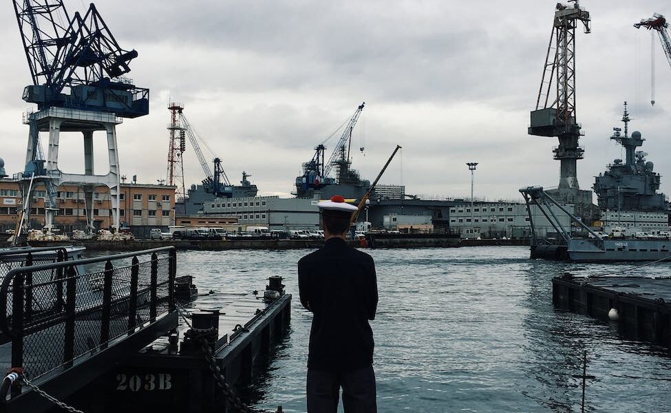 man standing and facing boats on water