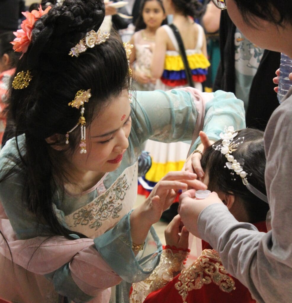 A woman in cultural outfit and makeup helping a young child with their makeup | Bishop Hamilton Montessori School in Ottawa