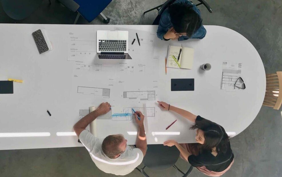 Blueprints and architectural plans on a large conference table.