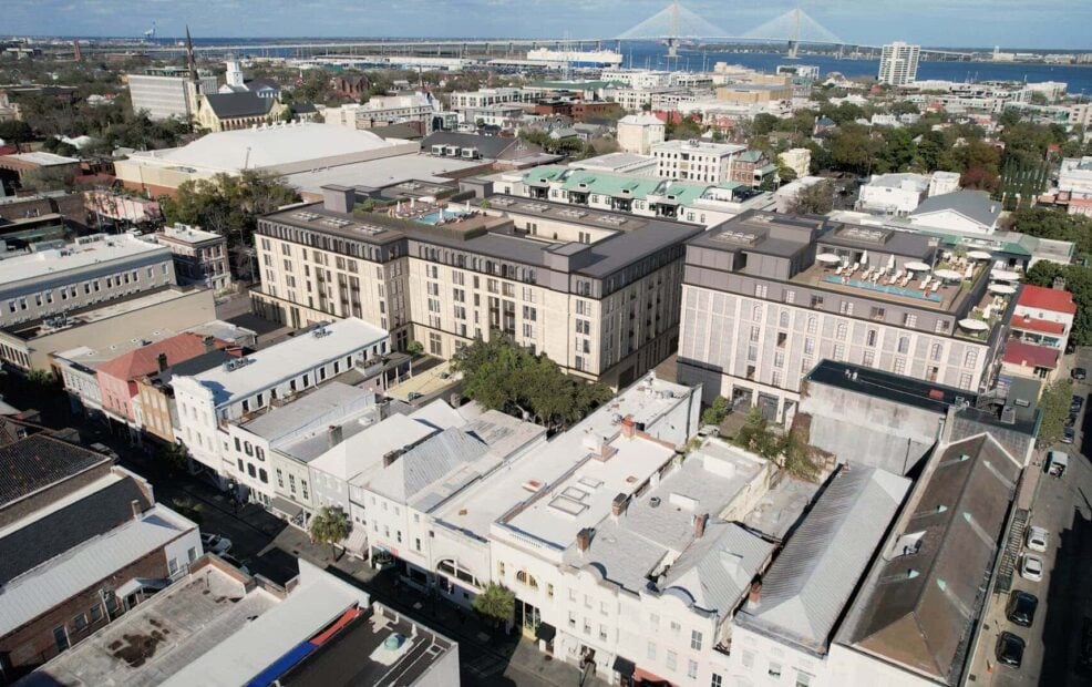 Modern mixed-use building with rooftop terraces, featuring a blend of classic and contemporary architecture, located in an urban setting with a bridge in the background.