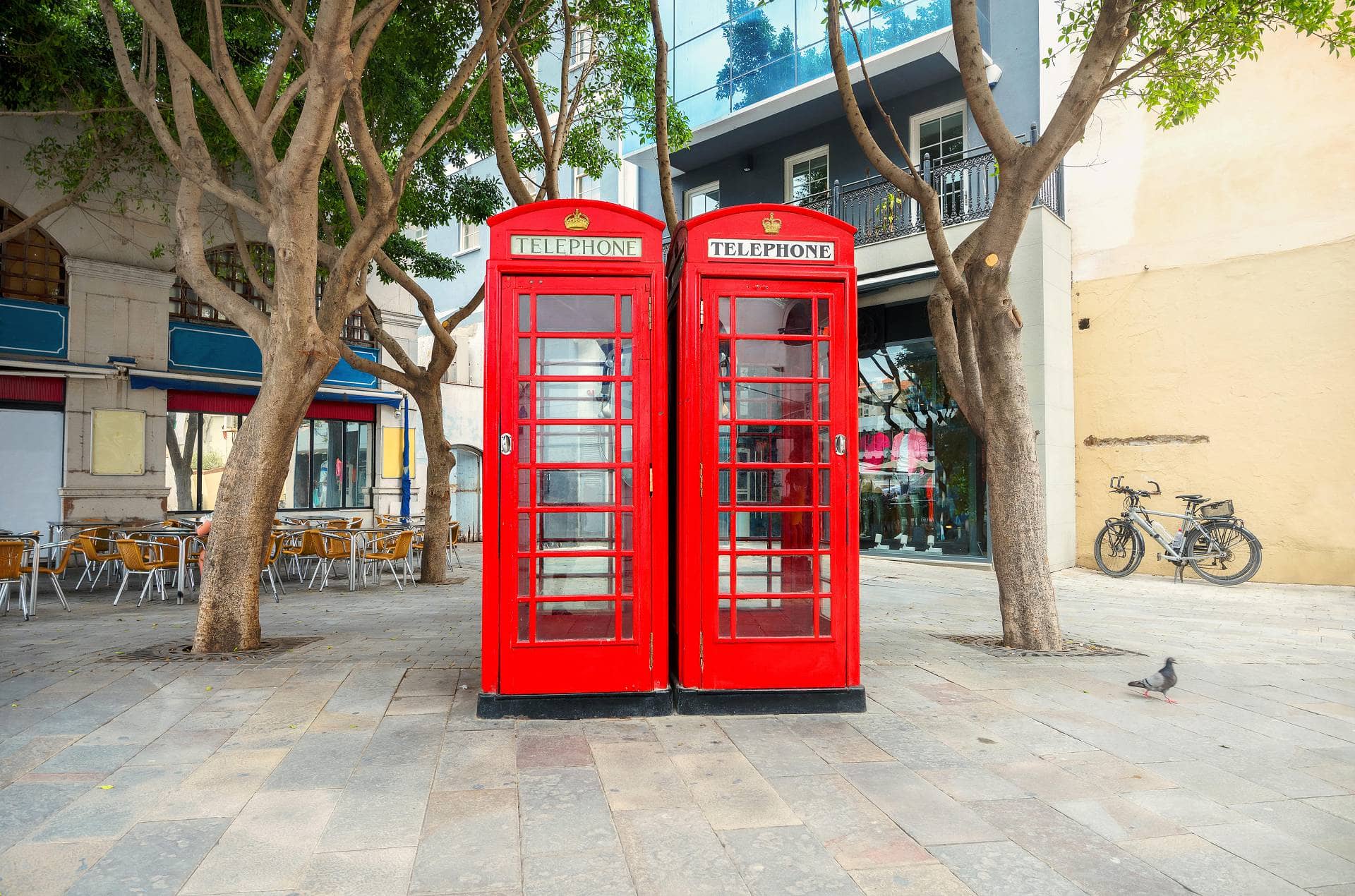 ДВЕ КРАСНЫЕ ТЕЛЕФОННЫЕ БУДКИ ПОД ДЕРЕВЬЯМИ В ГИБРАЛТАРЕ