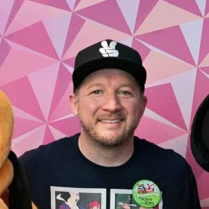 Disney characters Mickey Mouse and Pluto with a guest at a theme park.