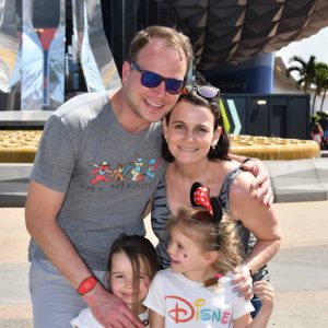 Smiling family at Disney theme park enjoying a fun day together.
