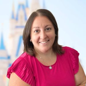 Smiling woman in pink blouse, promoting 407 and Beyond Vacation Co., expert in personalized vacation planning.