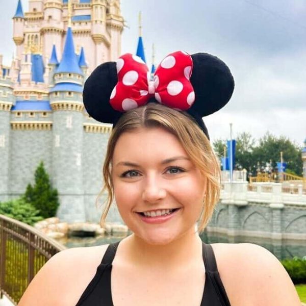 Minnie Mouse ears headband at Disney theme park, smiling woman enjoying magical vacation.