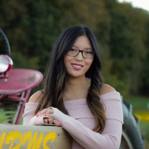 Vintage pink tractor at 407 and Beyond Vacation Co. with a cheerful woman enjoying farm life.