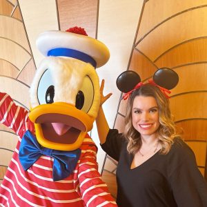 Woman with Disney's Donald Duck character at a themed event.