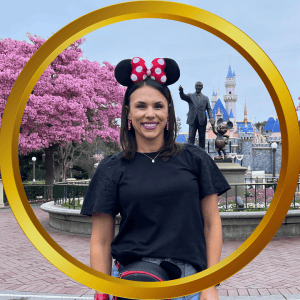 Woman wearing Minnie Mouse ears at Disneyland with castle in background.