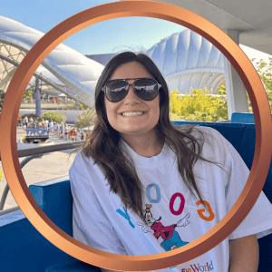 Woman enjoying a Disney World ride with a big smile and sunglasses.