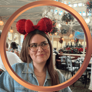 Girl with glasses and Minnie Mouse ears enjoying a Disney vacation celebration.