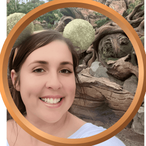 Relaxing vacation photo of a woman smiling outdoors with decorative spherical garden lights and natural wood scenery.
