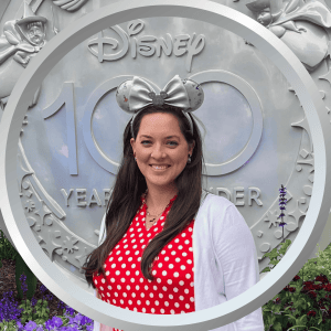 Disney 100th anniversary celebration, woman wearing Minnie Mouse ears and red polka dot dress.