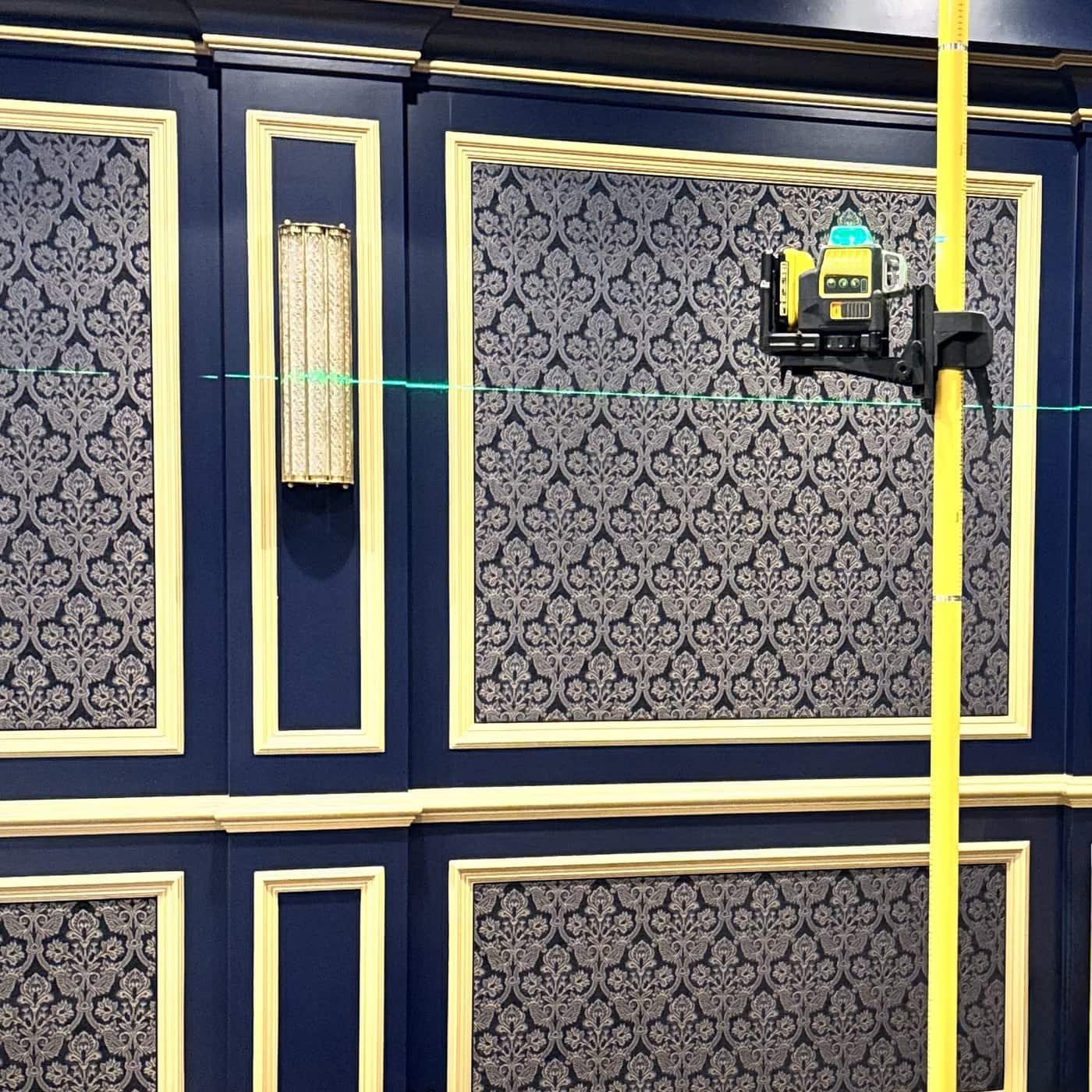 Home 2 Fabric-wrapped acoustic wall panels in gold frames on a navy theater wall, laser-leveled during installation by Acoustics Specialty