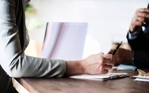 Person Holding A Pen Over Documents During A Professional Meeting