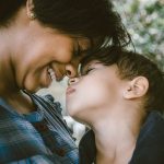 Mother Touching Noses With Her Young Son While Smiling