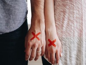 Couple With Red X Marks Painted On Their Hands