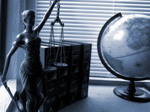 Lady Justice Statue With Scales Next To Law Books And A Globe