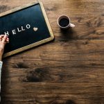 Blackboard Spelling Hello Beside A Cup Of Coffee On A Wooden Desk