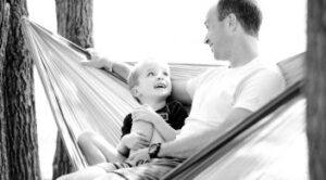 Father And Young Son Relaxing Together In A Hammock Outdoors