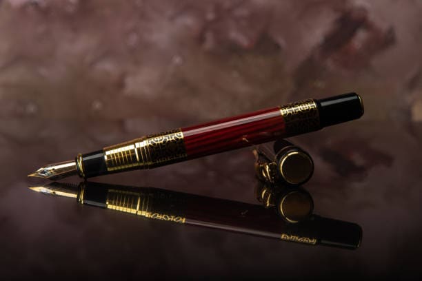 Image d'un stylo plume couleur or posée sur une surface qui le reflète.