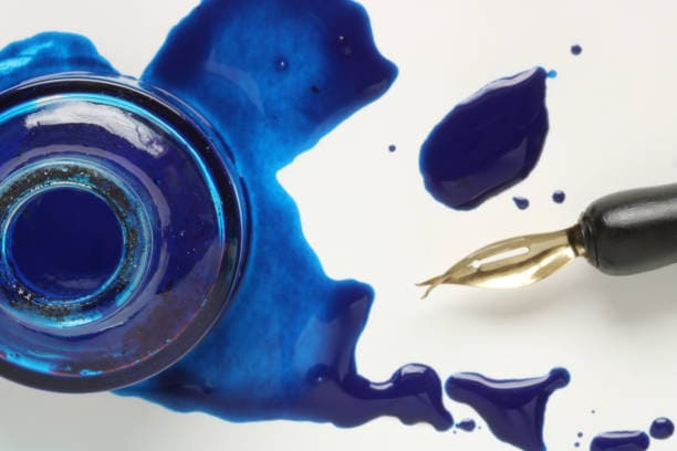 Image d'un encrier avec son encre bleue renversé et accompagner d'un stylo calligraphique. Image d'un encrier avec son encre bleue renversé et accompagner d'un stylo calligraphique. Image d'un encrier avec son encre bleue renversée, accompagner d'un stylo calligraphique.