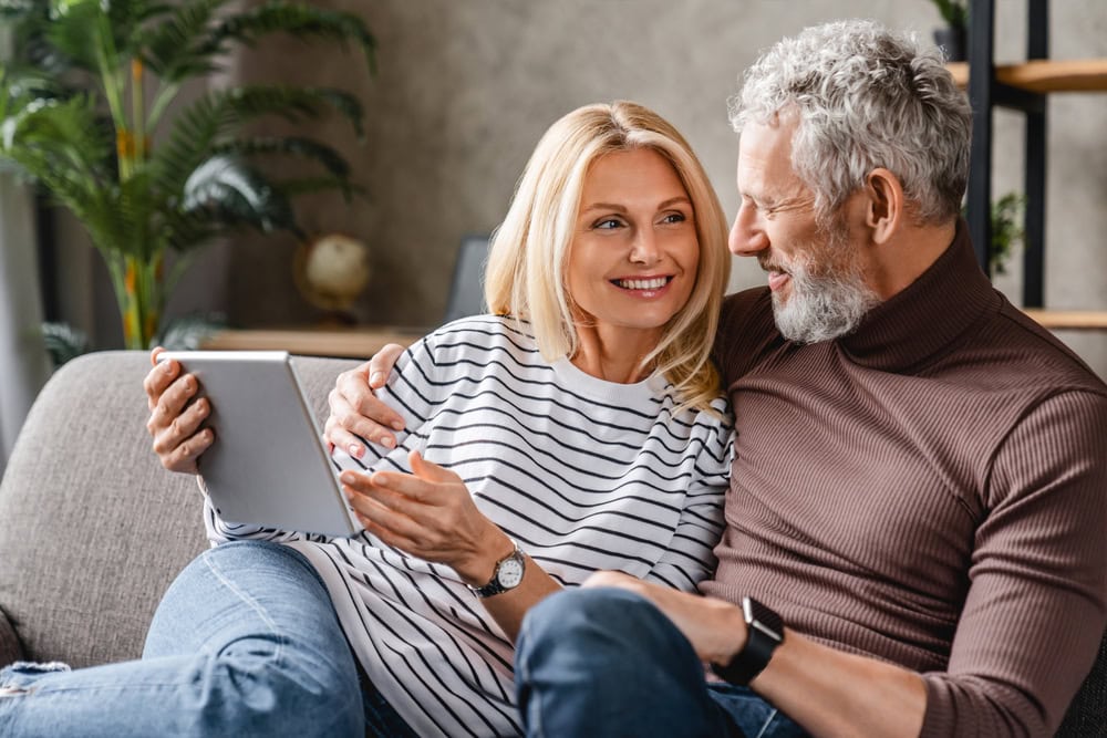 Happy,Middle,Aged,Couple,Using,Digital,Tablet,On,Sofa,At