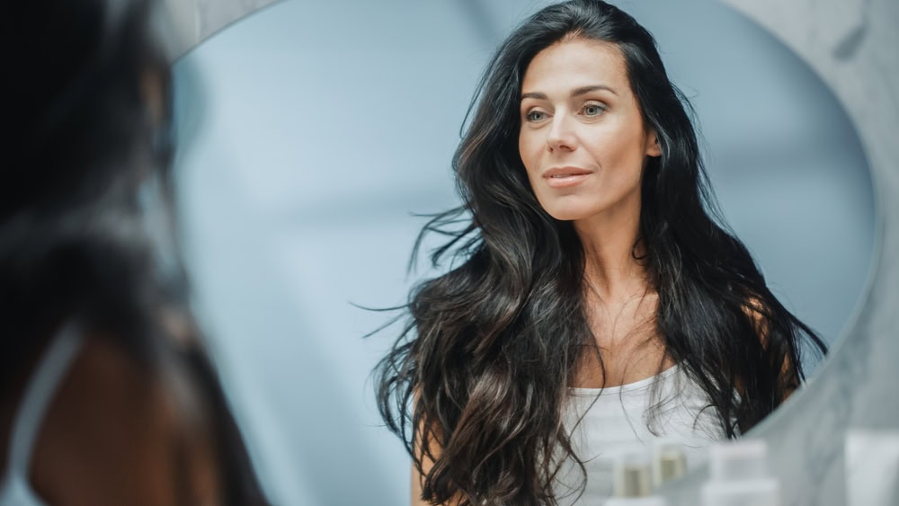 Beautiful,Caucasian,Middle,Aged,Woman,Looks,Into,Bathroom,Mirror,,Enjoys