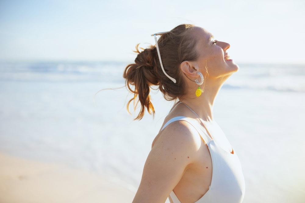 Smiling,Modern,Woman,In,White,Beachwear,At,The,Beach,Relaxing