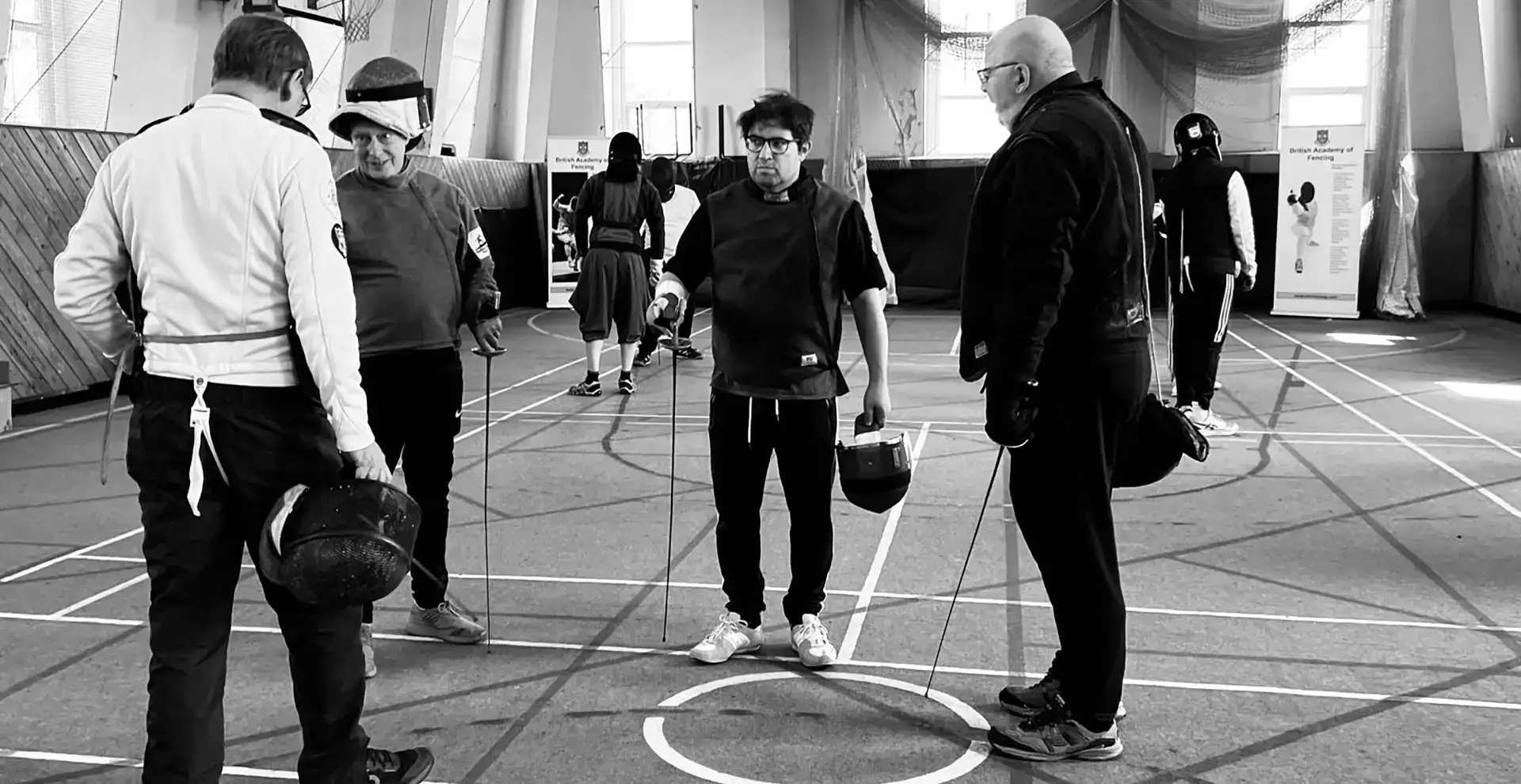 A group of trainee coaches receiving fencing instruction
