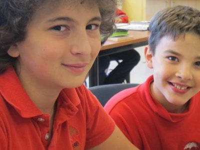 2 young boys in red shirts smiling at the camera | Bishop Hamilton Montessori School in Ottawa