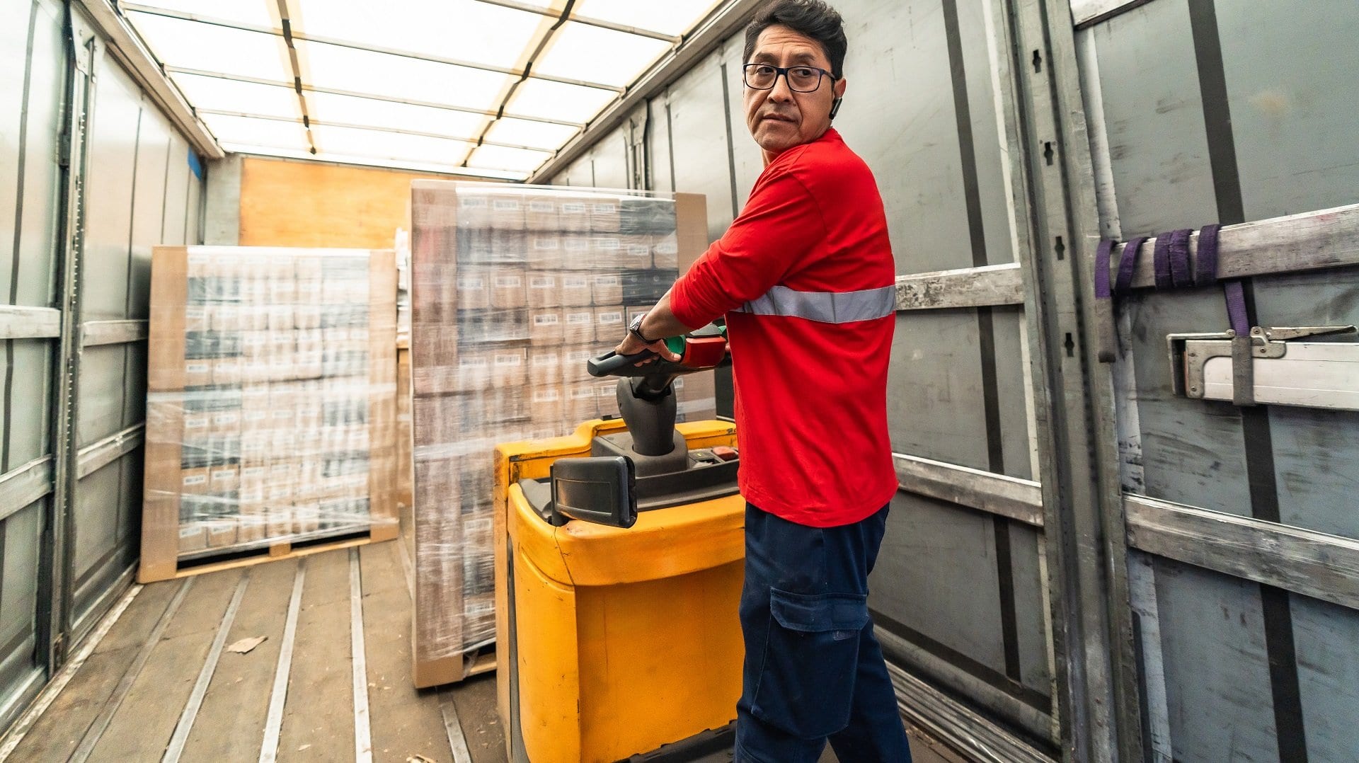 Latin man worker loading a delivery truck in distribution warehouse