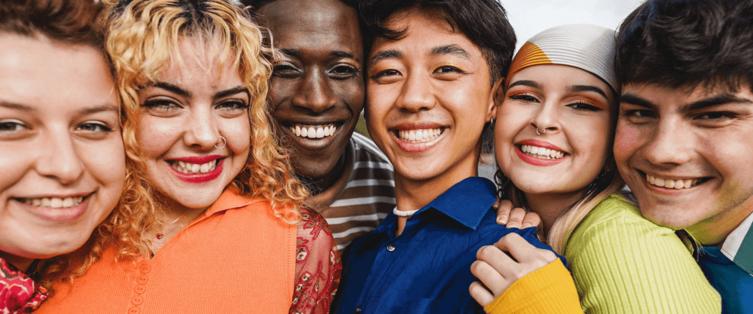 A diverse group of people with different ethnicities and genders smiling and wearing bright, colourful clothing, symbolising inclusivity and joy.