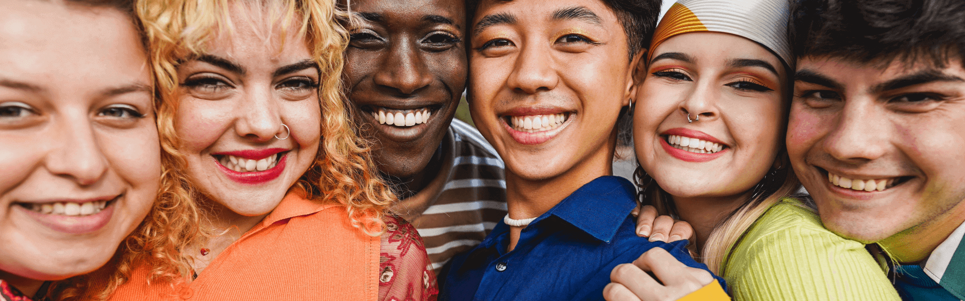 A diverse group of people with different ethnicities and genders smiling and wearing bright, colourful clothing, symbolising inclusivity and joy.